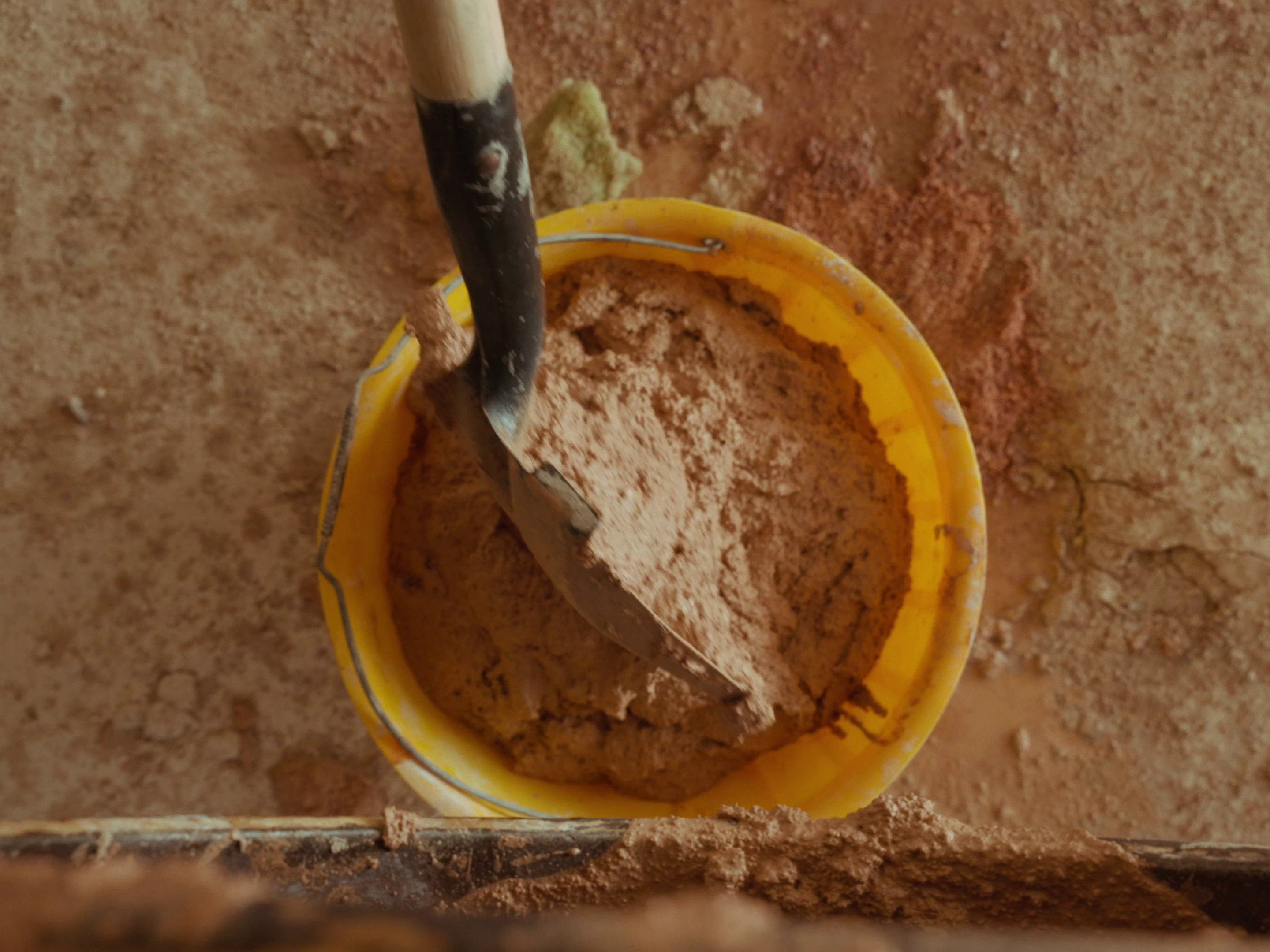 The mix being transferred to a bucket with a shovel after it was done mixing.